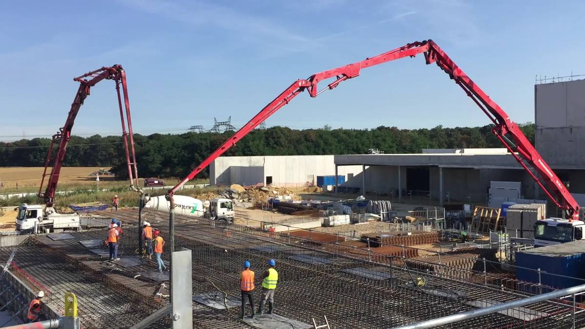 Deux pompes à béton automotrices alimentant le coulage d'une grande dalle ferraillée